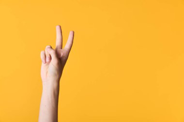 Canlı sarı bir arkaplan karşısında barış jesti, jestin, zaferin ve reklamcılığa, eğitime veya motivasyonel içeriğe uygun neşeli havanın vurgulandığı minimum çekim.