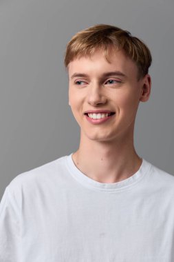 Beyaz tişörtlü, güler yüzlü bir adamın pazarlama, takım ve müşteri için samimiyet, iyimserlik ve güvenilirlik içeren görüntüsü..