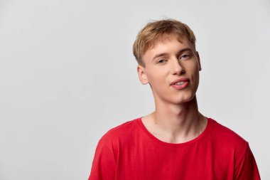 Kırmızı tişörtlü gülümseyen bir erkek mankenin, markalaşma kampanyaları için ideal tarafsız bir arkaplan ve neşeli görsel yaklaşımlara ihtiyaç duyan editoryal kullanım için yakın çekimi.