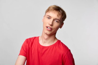 Stüdyo ortamında kırmızı tişört giyen sıradan bir genç, pazarlama, moda ve editoryal kullanım için yaklaşılabilir, modern ve günlük bir cazibe sergiliyor.