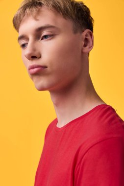 Kırmızı tişörtlü, parlak sarı arkaplanlı genç bir adama yaklaş. Ticari kullanım için çağdaş tarzı, temiz cildi, günlük güveni ve stüdyo fotoğrafçılığını vurgula.