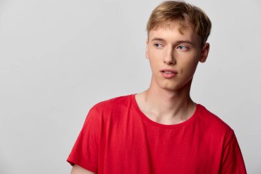 Kırmızı tişörtlü, düşünceli bir adam, stüdyo ışığı, tarafsız zemin, modern tarz ve moda, yaşam tarzı veya ticari kavramlar için çok yönlü ruh hali.