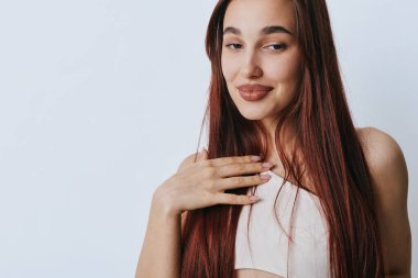 Uzun saçlı, göğsüne dokunan ve gözleri kapalı gülümseyen genç bir kadının portresi. Doğal güzellik, sakin ruh hali ve basit bir geçmişi olan sıradan bir tarz..