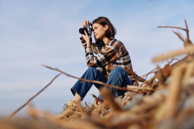 Fotoğrafçılık, fotoğrafçılık, doğa, kamera, lens, oturma, kadın keşif, manzara, sonbahar, rüzgar, gün ışığı, odaklanma. Sahilde sakin bir portre. Ekipmanlar hazır.
