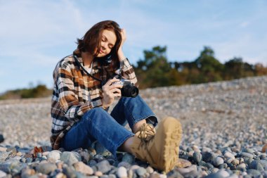 Kayalık bir kıyı şeridinde sıradan bir fotoğrafçı ufku keşfederken kepenk detaylarına odaklanıyor. Kalıplı taşlar, mavi gökyüzü ve gevşemiş giysiler rahatlığı, keşfi ve yaratıcılığı iletir.