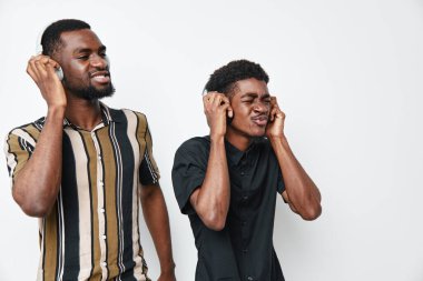 Siyah tenli Afro-Amerikalı erkekler kulaklık takıyor, müzik ve coşkuyla dans ediyor, beyaz arka planda izole edilmiş günlük giysiler ve gülücüklerle..