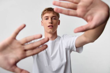 Ellerini objektife doğru uzatan genç bir adama yakın çekim yapmak, yüksek kontrastlı bir stüdyo sahnesinde derinlik, enerji ve bağlantı yaratmak.