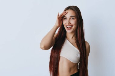 Alnına yakın el ele tutuşmuş, uzun düz saçlı mutlu kadın başka tarafa bakıyor. Neşeli bir kadın portresi, günlük kıyafetler ve beyaz arka planda parlak bir gülümseme..