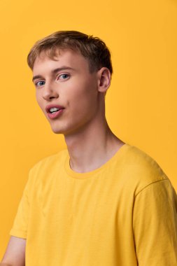Sarı gömlekli bir adam, canlı sarı bir arka plana karşı, basit moda cazibesini, gençlik enerjisini ve yaklaşılabilir enerjiyi vurguluyor. Stüdyo ışıklandırması ve düzensiz çerçeve desteği ticari yaşam tarzı