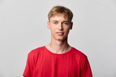 Kırmızı tişörtlü, stüdyo arka planlı, aydınlık, arkadaş canlısı, yaşam tarzı kampanyaları, ürün gösterileri ya da çevrimiçi kataloglar için ideal genç bir erkek modelin günlük moda görüntüsü.