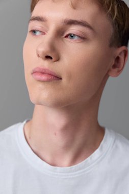 Genç erkek, sakin ifade, berrak ten ve nazik gölgeler içeren yakın çekim, gözler ve dudaklar gibi yüz hatlarına vurgu, reklamlar ve editör projeleri için uygun