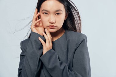 Ciddi bir Asyalı kadın portresi koyu düz saçlı ve gri örgü örgü örüyor. Yüzü düz ışığa değiyor. Tarz, güzellik, moda ve model konsepti için..