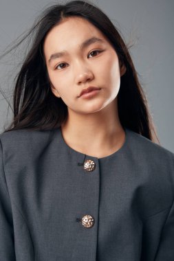 Sade, tarafsız bir zemine karşı duran gri saçlı sakin bir genç kadının portresi. Minimum makyaj, basit stil ve yüz ve kıyafet dokusu..