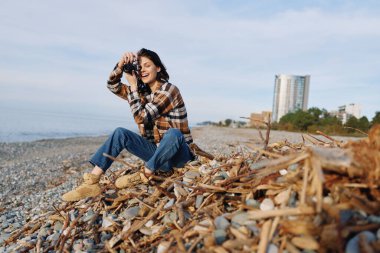 Dürbün, kot pantolon ve ekose bluz, hafif deniz meltemi, mavi gökyüzü, manzara titreşimi, keşif ve merakın arasında kıyı şeridini inceleyen bir kadın sahnesi