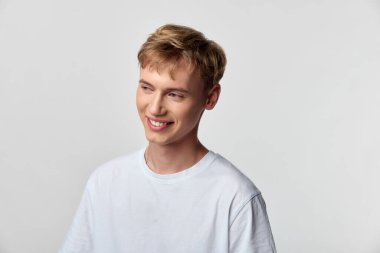 Minimalist bir stüdyoda beyaz tişört giyen, markalaşma, reklamcılık, sağlık ve gençlik yaşam tarzı projelerine uygun gülümseyen bir adamla sıradan bir ortam.