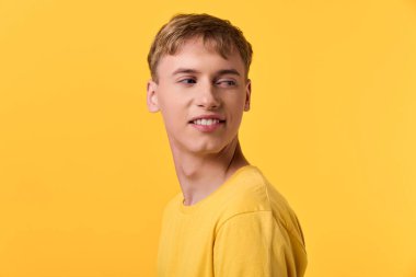 Sarı tişörtlü erkek çocuk rahat bir hava ve sıcak bir tonla poz veriyor, canlı renkleri, günlük kıyafetleri ve yaratıcı stok tasvirleri ve markalaşma projeleri için iyimser tavırları vurguluyor.