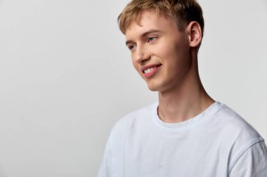 Beyaz tişörtlü, gülümseyen, rahat duruşu ve yaklaşılabilir tavrı olan, yaşam tarzı, sağIık ve pozitif mesajlaşma için ideal bir genç adamın yer aldığı rahat ve rahat bir sahne.