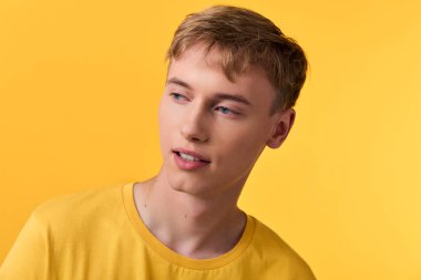 Sarı tişört giyen sıradan bir erkek figürü canlı sarı bir arka plan, düşünceli bakışlar, basit bir düzen, modern tarz, doğal ışıklandırma, moda ve pazarlamaya uygun minimum sahne