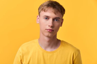 Genç adam, sarı gömlek, sarı arka plan, ön manzara, stüdyo çekimi, günlük kıyafet, yüz ifadesi, doğal ışıklandırma, yaşam tarzı, ürün veya moda kullanımı için modern tarz vurgu