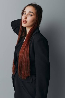 Siyah ceketli genç bir kadının portresi. Uzun saçlı, el ele duran bir kadın. Modern moda, güzellik ve stil konsepti doğal makyaj ve rahat poz..