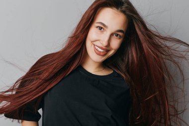 Tarafsız zemine karşı siyah bluzlu, kızıl saçlı, gülümseyen bir kadın. Kendine güveni tam genç bir kadın portresi. Gevşek saçları ve parlak bir ifadesi var..