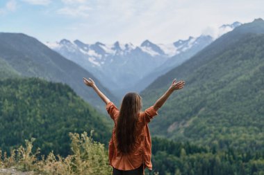woman, mountains, nature, outdoors, adventure, freedom, inclusive authentic traveler with arms raised overlooking valley slopes, authenticity inclusivity peaceful calm view