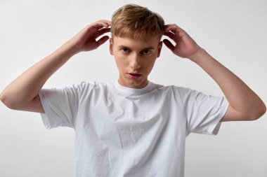 Moda ve tımar malzemesi için bir stüdyo ortamında saç, erkek ve tişört, özgüvenli ifade, günlük kıyafet, temiz fon, yaşam tarzı, editör veya pazarlama görselleri için çok yönlü günlük sahne