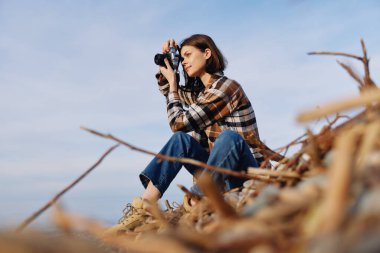 Ekose gömlekli sıradan bir fotoğrafçı, deniz esintisini ve geniş gökyüzünü yakalar, doğal dokular ve sakin kıyı manzarasıyla samimi bir alıştırma yapar..