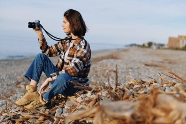 Bir sahil manzarası ve deniz ufkunda çakıl taşları, ahşap ve açık gökyüzü ile çevrili el kamerasıyla doğa ve seyahat temaları ile günlük gezgin fotoğrafçı..