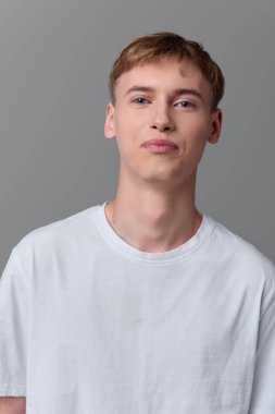 Gri arka planda beyaz tişörtlü genç erkek, samimi ve sakin görünüm, moda yaşam tarzı ya da ürün fotoğrafçılığı koleksiyonları için uygun en temiz tasarım