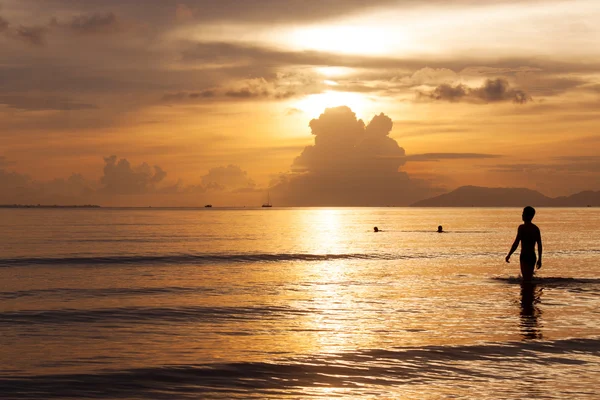 日没時に海で泳ぐ人たち ロイヤリティフリーのストック画像