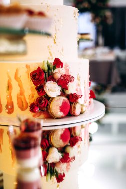 Pasta, kurabiye, tatlı ve yuvarlak bir masada çiçeklerle süslenmiş meyveli çikolata.