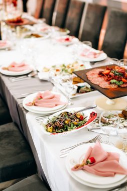 Restoranda atıştırmalık ve çiçeklerle şenlik masası. Misafirler için düğün masası dekorasyonu