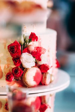 Pasta, kurabiye, tatlı ve yuvarlak bir masada çiçeklerle süslenmiş meyveli çikolata.