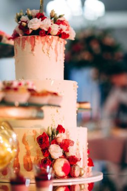 Pasta, kurabiye, tatlı ve yuvarlak bir masada çiçeklerle süslenmiş meyveli çikolata.
