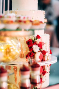 Pasta, kurabiye, tatlı ve yuvarlak bir masada çiçeklerle süslenmiş meyveli çikolata.