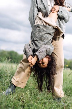 Anne ve kızı birlikte eğleniyor. Doğada haftasonu çimlerin arasında, ormanın yakınında