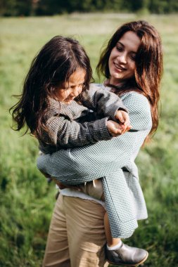 Anne ve kızı birlikte eğleniyor. Doğada haftasonu çimlerin arasında, ormanın yakınında