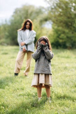 Anne ve kızı birlikte eğleniyor. Doğada haftasonu çimlerin arasında, ormanın yakınında