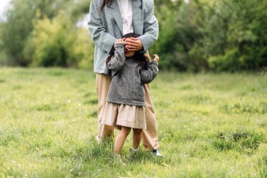 Anne ve kızı birlikte eğleniyor. Doğada haftasonu çimlerin arasında, ormanın yakınında