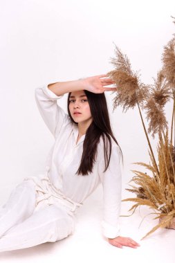 Beyaz doğal çevre kıyafetleri içinde güzel bir kız, arka planda poz veriyor. Çevre dostu kıyafet konsepti