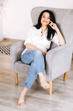 Evdeki sandalyede beyazlar içinde güzel bir esmerin portresi.