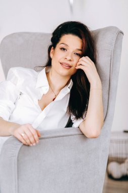 Evdeki sandalyede beyazlar içinde güzel bir esmerin portresi.