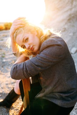 Gün batımında kumlu bir kanyonda eski bir sandalyede oturan kızıl saçlı kız. Yalnızlığın psikolojik portresi. Hipster eski moda konsepti