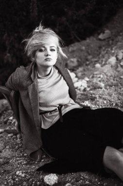 Gün batımında kumlu bir kanyonda eski bir sandalyeyle poz veren kızıl saçlı kız. Yalnızlığın psikolojik portresi. Hipster eski moda konsepti