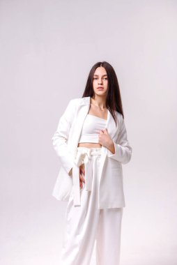 Beyaz bir arka planda beyaz eko elbiseli güzel bir esmerin moda portresi.