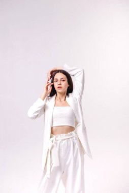 Beyaz bir arka planda beyaz eko elbiseli güzel bir esmerin moda portresi.