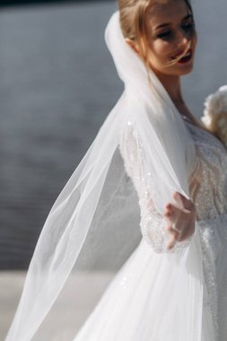 Güneşli bir günde, nehrin kenarında gelinlik giymiş nazik bir gelinin portresi. Yumuşak odak