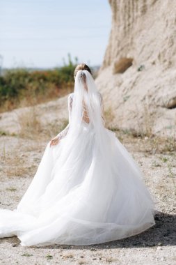 Düğün günü kayaların yanında bir gelin portresi ve lüks bir elbise.