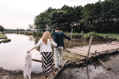 Yakışıklı bir adam ve sarışın bir kız nehir ve ormanın yakınındaki çimlerde yürüyorlar. İnekler ve atlarla otlağın arka planında el ele tutuşup gülümsüyorlar.